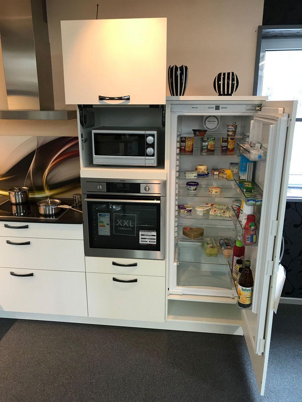 Unsere Ausstellung in Bischberg — Weiße Küchenzeile mit Mikrowelle und geöffnetem Einbaukühlschrank gefüllt