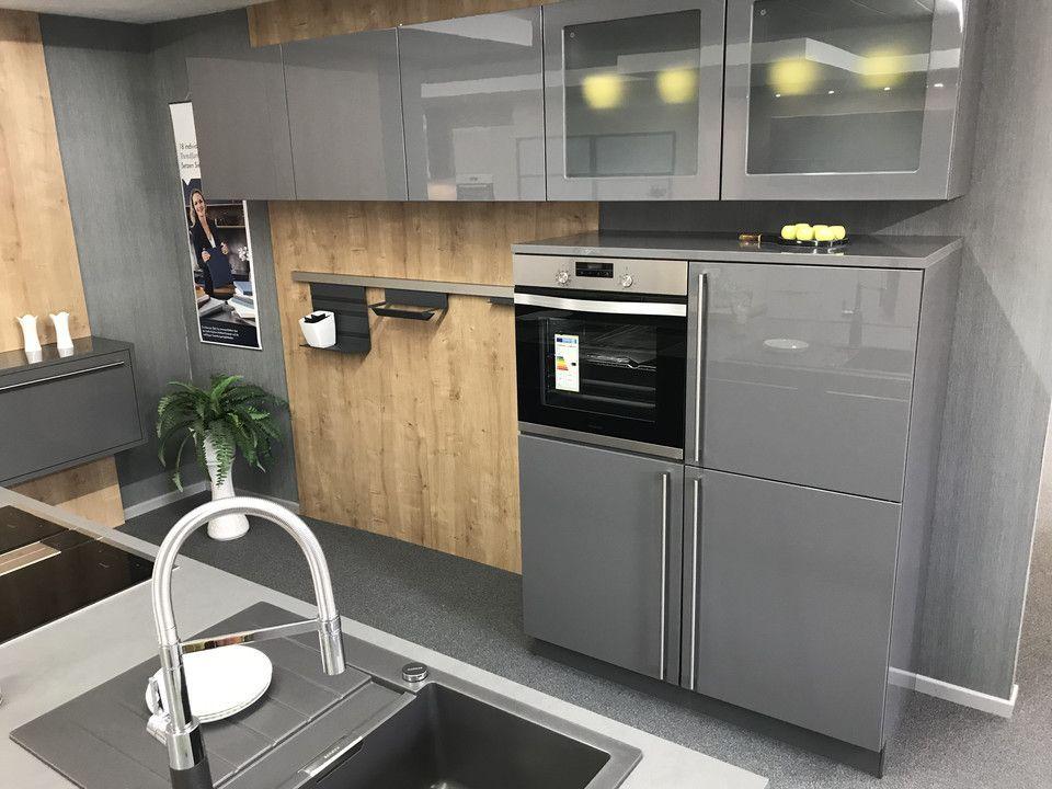 Unsere Ausstellung in Bischberg — Graue Hochglanzküche mit Holz-Nischenwand, Einbaubackofen und Edelstahl-Armatur