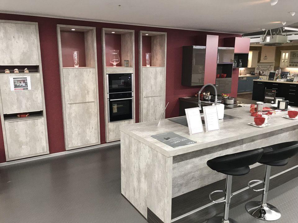 Unsere Ausstellung in Bischberg — Showroomküche in Beton-Optik mit Halbinsel, Hochschränken, schwarzen Barhockern